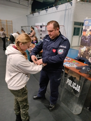 Policjant przedstawiający dzieciom sprzęt policyjny